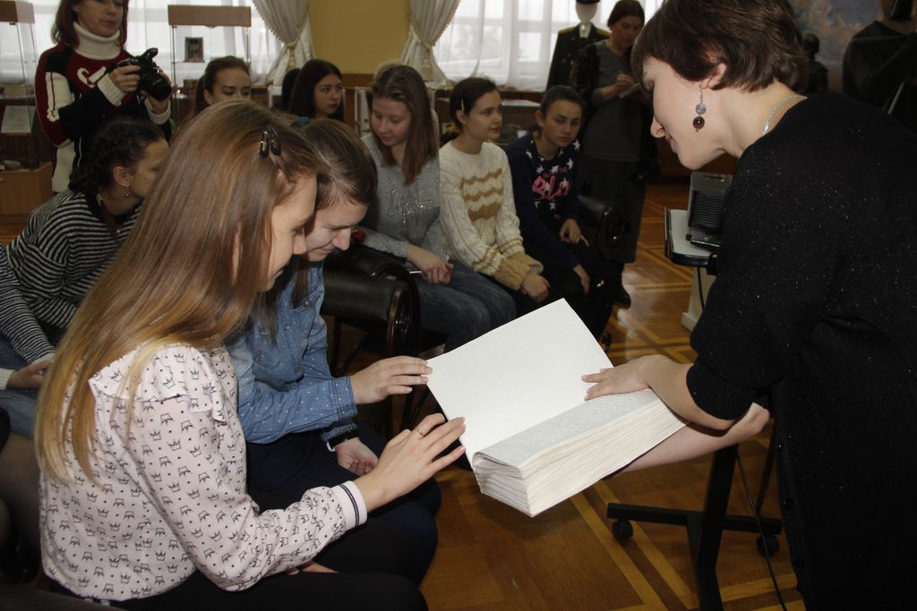 Молодые волонтёры читают свои первые книги по брайлю