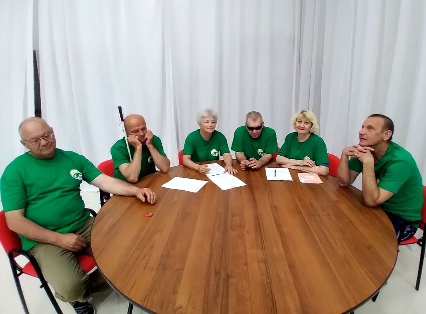 участники викторины музыкальный эрудит - команда из шести человек (две женщины, четыре мужчины) в зеленых футболках сидит за круглым столом