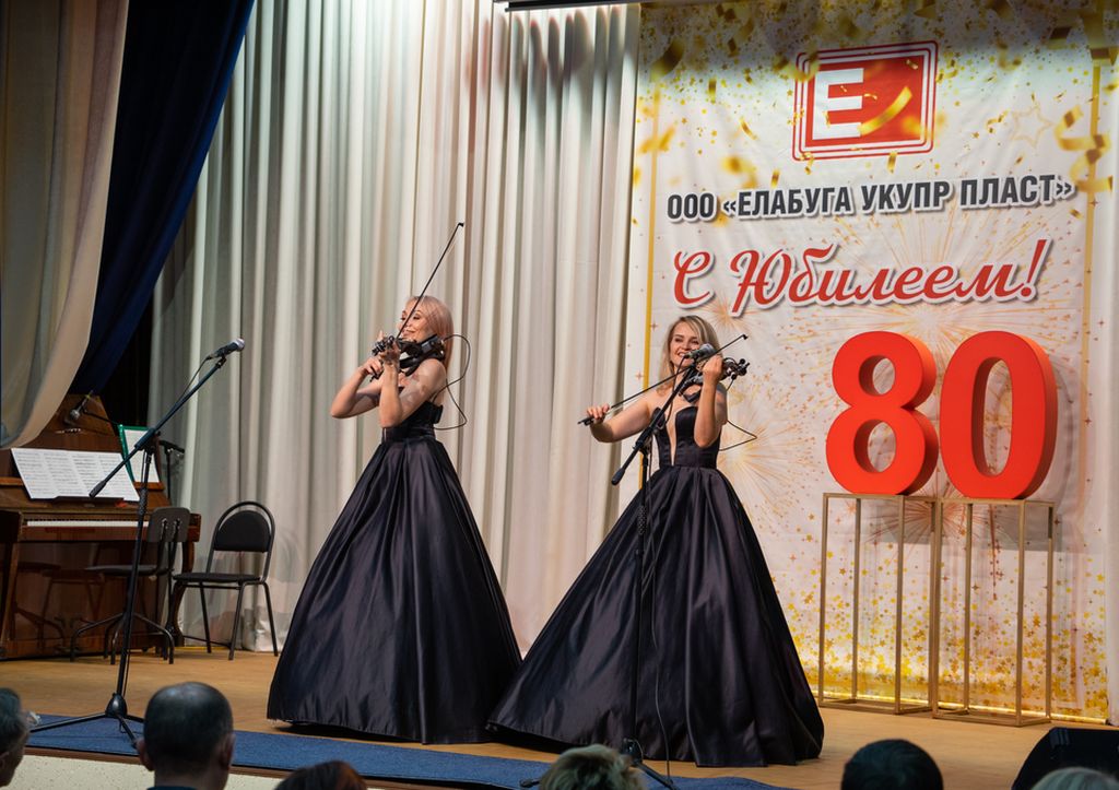 На сцене две девушки в длинных пышных чёрных платьях до пола играют на электроскрипках.