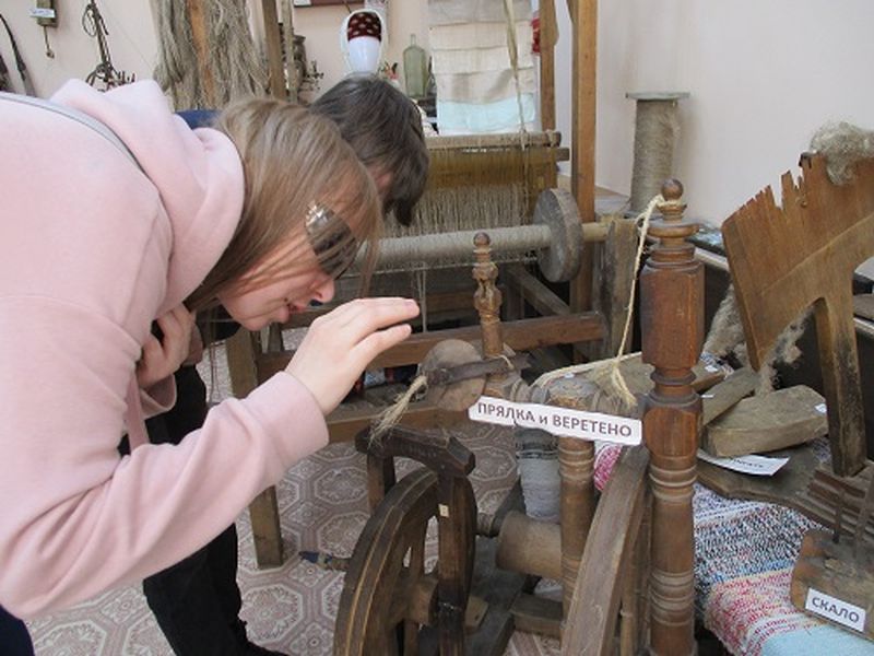 Молодые активисты ВОС прикасаются к предметам старины в музее 