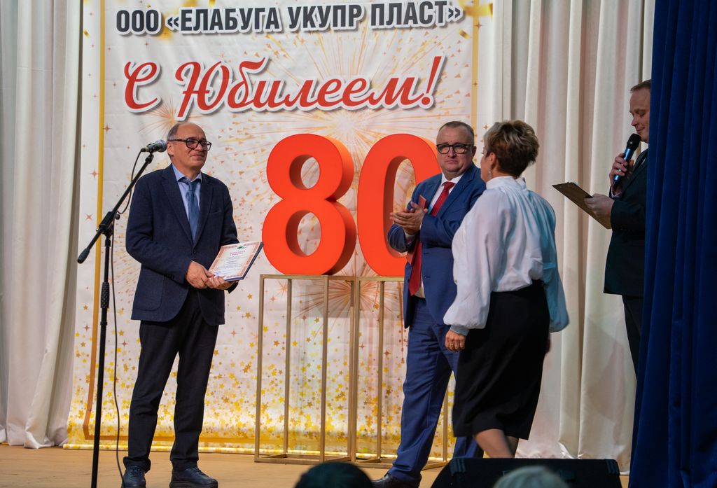 На сцене Д. В. Котенев вручает сотруднице предприятия почётную грамоту ЦП ВОС.