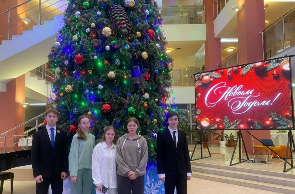 Ребята стоят на фоне новогодней ёлки