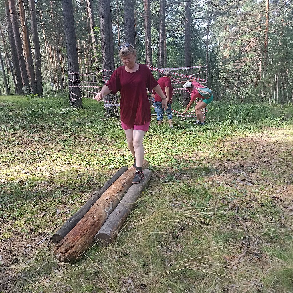 Одна из участниц слёта проходит по бревну