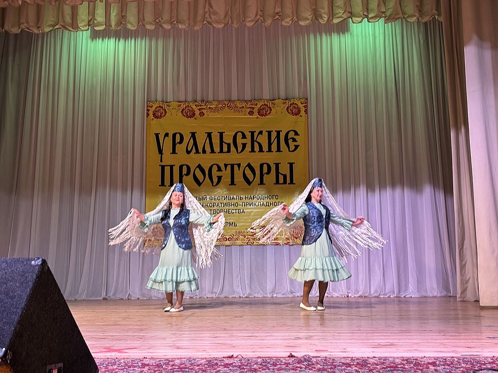 на сцене 2 танцовщицы и баннер с названием фестиваля