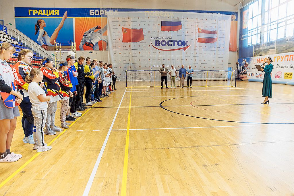 Спортсмены, представители трёх сторон и ведущая мероприятия в спортивном зале