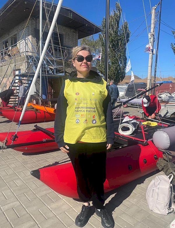 женщина в жёлтом жилете стоит на фоне катамарана