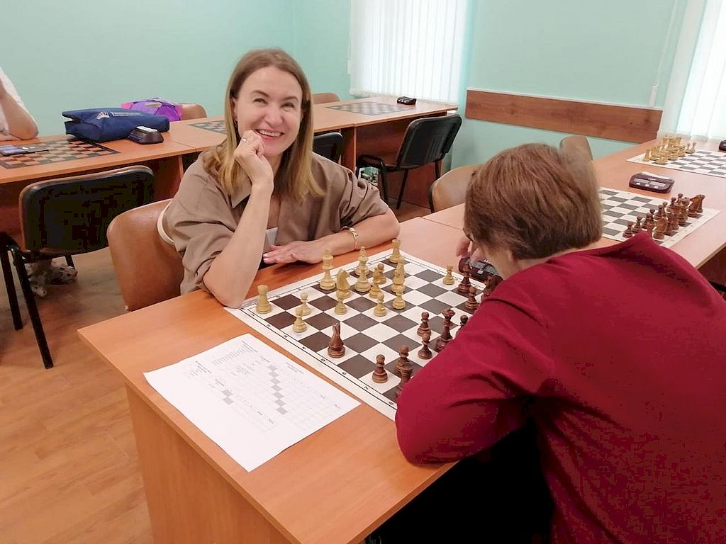 Две женщины сидят друг напротив друга. Между ними игровая доска.
