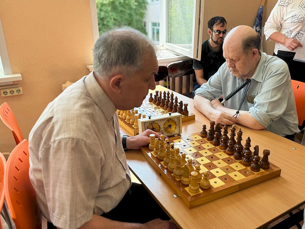 Игровой момент. За столом друг напротив друга сидят двое мужчин.