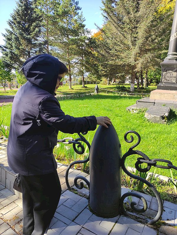 участник экскурсии осматривает снаряд