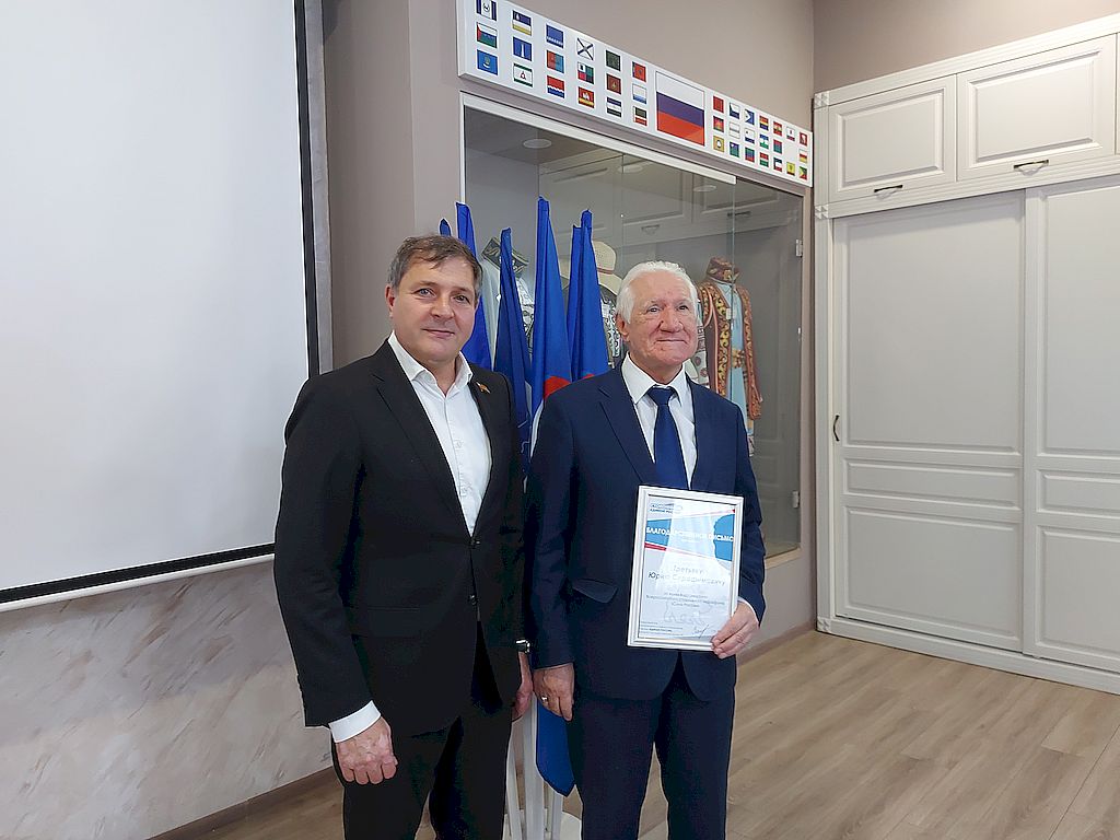 Юрий Серафимович Третьяк с грамотой. Рядом стоит мужчина в тёмном костюме