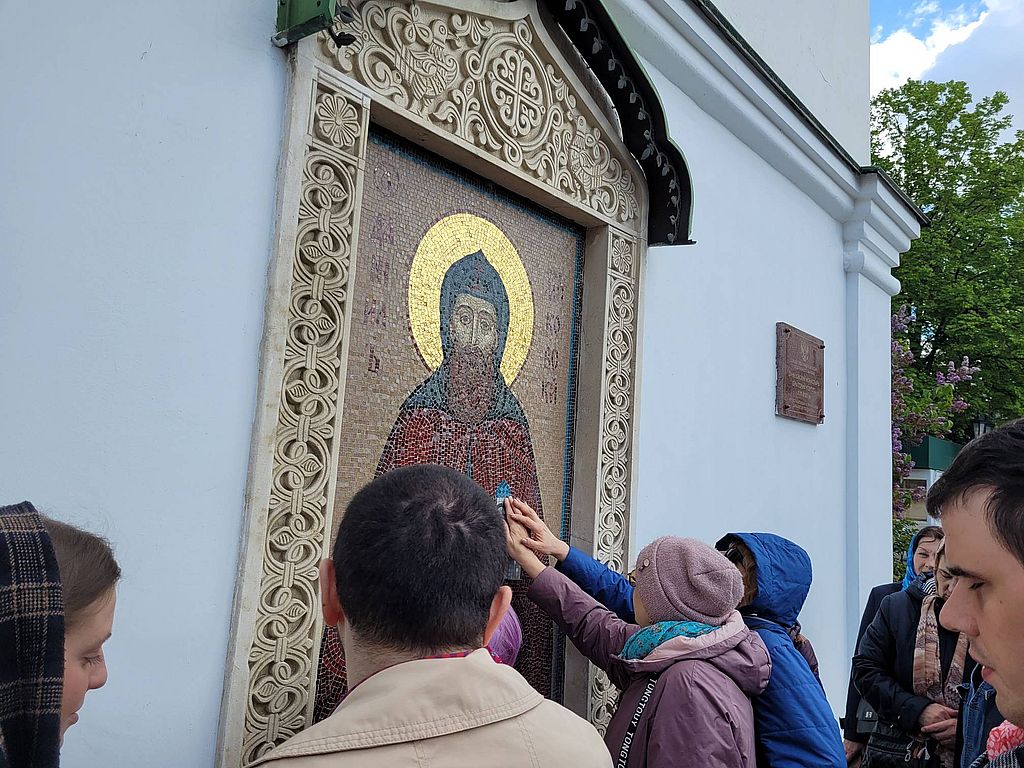 экскурсанты осматривают икону на стене храма