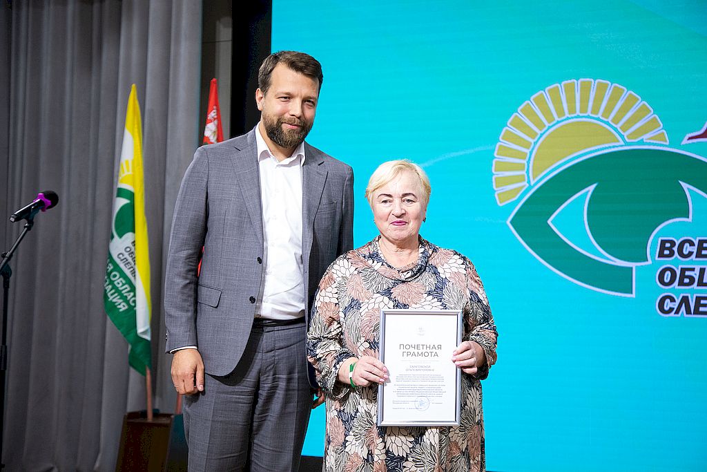 Заместитель Министра социального развития Московской области Евгений Ермилов торжественно вручает Почётную грамоту Министерства председателю Подольской местной организации ВОС, председателю КРК МОО ОООИ ВОС, члену Центральной контрольно-ревизионной комиссии ВОС Ольге Саратовской