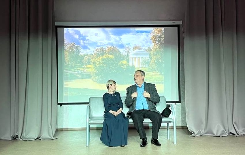 чтецы - мужчина и женщина сидят на скамейке, на экране осенний пейзаж