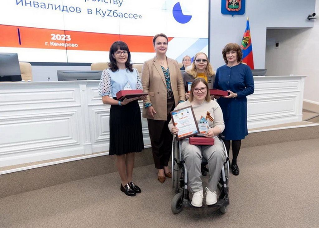 Председатель Кемеровской РО ВОС И. А. Крюкова  и другие победители номинации с председателем Совета по вопросам попечительства в социальной сфере Кузбасса А. Е. Цивилевой. В руках у победителей дипломы. Одна из них в инвалидной коляске. 