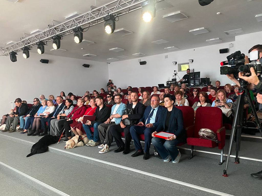 В зале сидят люди с собаками