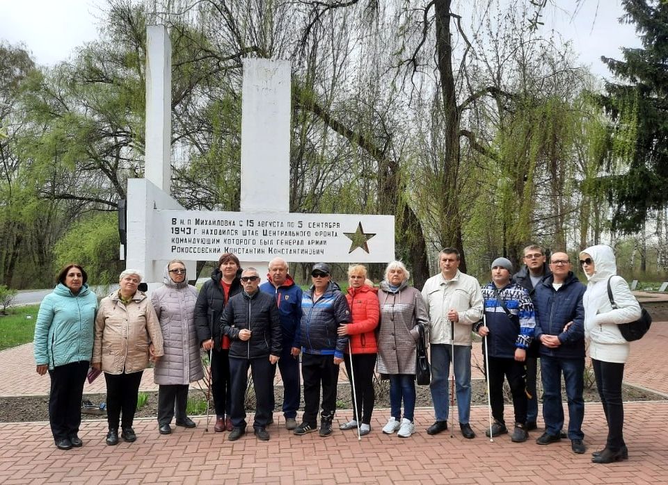 Участники проекта - инвалиды по зрению - стоят возле памятника, посвященному Великой Отечественной войне,  в частности генералу армии Константину Рокоссовскому.