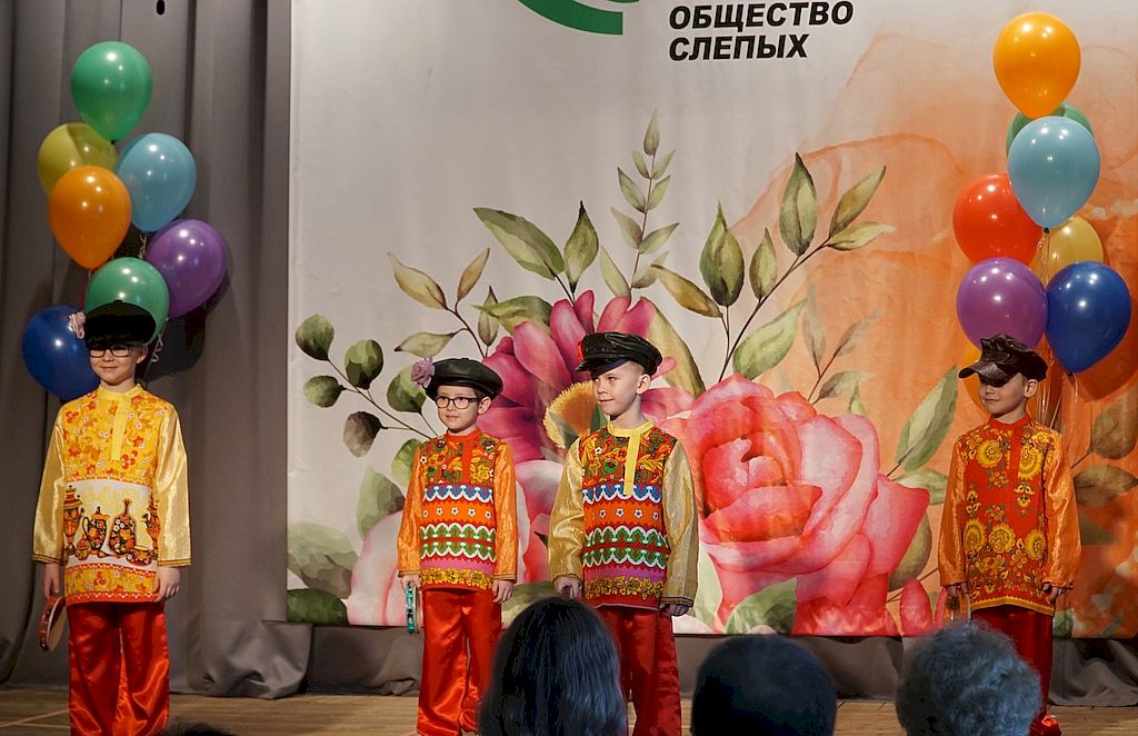три мальчика стоят на сцене в ярких костюмах.