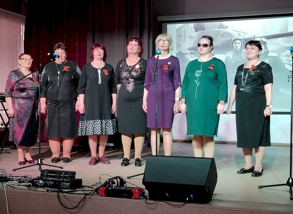 Семь представительниц Исилькульской местной организации ВОС стоят на сцене. Все они одеты в платья ниже колена.