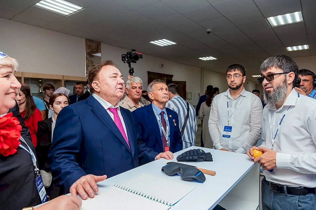 Фотография с презентации проекта. На столе перед участниками презентации лежат перчатки и повязка на глаза для игры в настольный теннис для незрячих