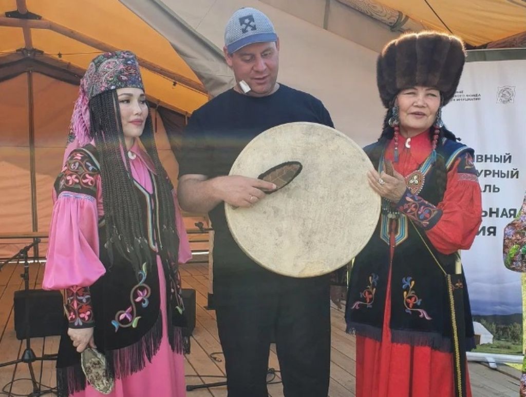 Член Хакасской РО ВОС держит шаманский бубен в окружении девушек в национальных костюмах